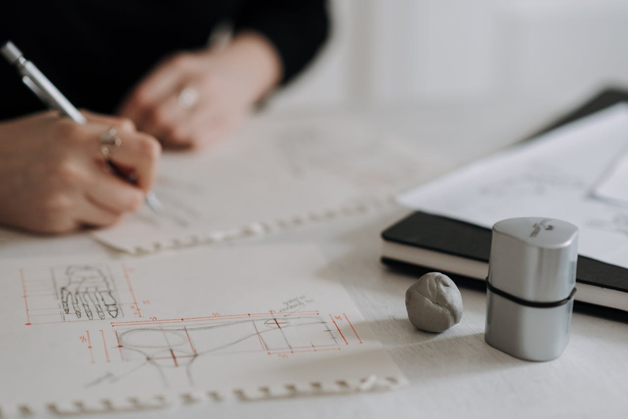 Detailed hand sketching on architectural blueprints with drawing tools and notebook.